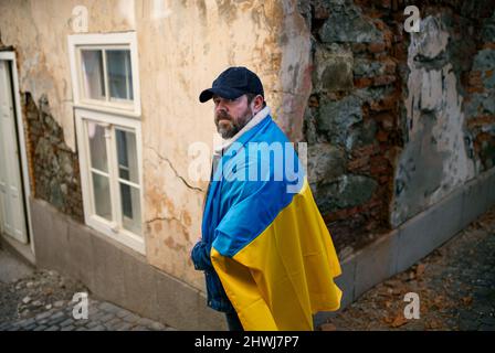 Protestante coperto di bandiera Ucraina blu e gialla che protestano contro la guerra in Ucraina per strada Foto Stock