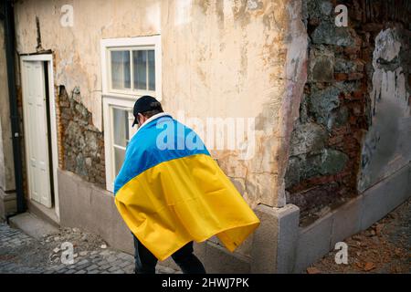 Protestante coperto di bandiera Ucraina blu e gialla che protestano contro la guerra in Ucraina per strada Foto Stock