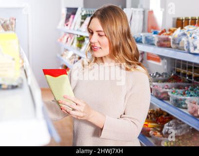 Donna che sceglie le spezie in drogheria Foto Stock