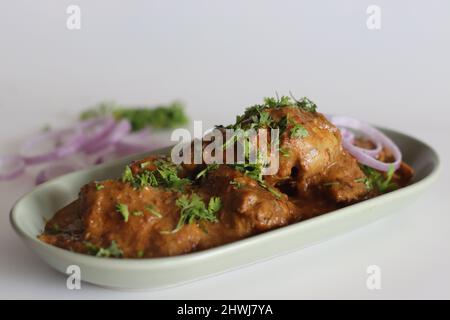 Curry di pollo preparato con pollo in salsa di cashew guarnito con foglie di coriandolo fresco. Scatto su sfondo bianco Foto Stock