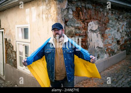 Protestante coperto di bandiera Ucraina blu e gialla che protestano contro la guerra in Ucraina per strada Foto Stock