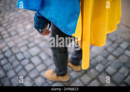 Lowsection del protestor coperto con bandiera Ucraina blu e gialla che protestava contro la guerra in Ucraina per strada Foto Stock