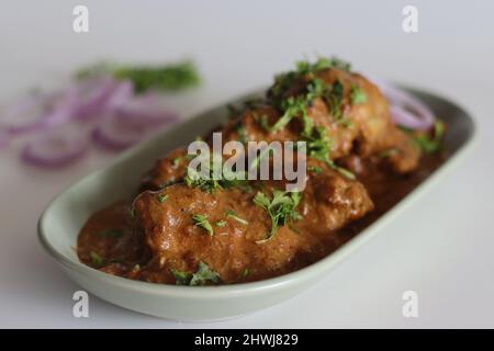 Curry di pollo preparato con pollo in salsa di cashew guarnito con foglie di coriandolo fresco. Scatto su sfondo bianco Foto Stock