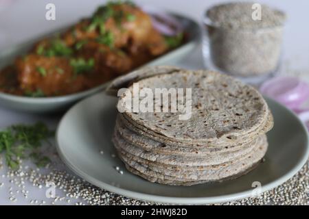 Pane morbido e piatto fatto di farina di miglio di perla. Servito con pollo in salsa di cashew guarnito con foglie di coriandolo fresco. Scatto su sfondo bianco. Comun Foto Stock