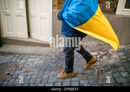 Lowsection del protestor coperto con bandiera Ucraina blu e gialla che protestava contro la guerra in Ucraina per strada Foto Stock