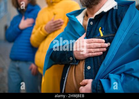 Sparato di manifestanti con nastri e bandiere ucraini blu e gialli che protestano contro la guerra in Ucraina per strada Foto Stock