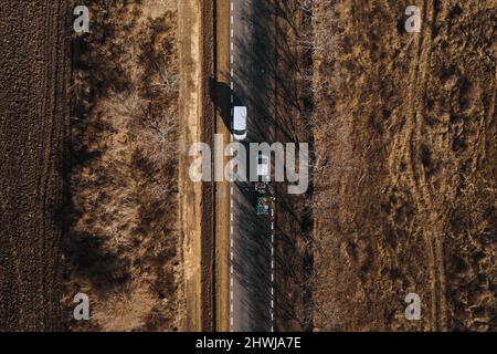 I lavoratori della strada utilizzano le macchine per dipingere i cartelli trafic su una superficie asfaltata fuori dalla città. Segnaletica stradale. Lavoratori e spruzzatori di vernice per strade. Foto Stock