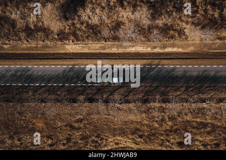 I lavoratori della strada utilizzano le macchine per dipingere i cartelli trafic su una superficie asfaltata fuori dalla città. Segnaletica stradale. Lavoratori e spruzzatori di vernice per strade. Foto Stock