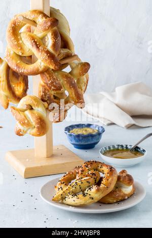 Pretzel fatti in casa serviti con senape tuffo e una torre di loro in dietro. Foto Stock