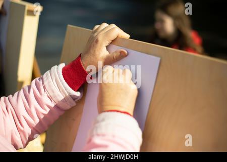 Artista dipinge su strada. La mano tiene la matita. Belle arti . Le mani della donna e malbert. Disegno verticale. Foto Stock