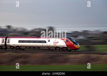 Virgin Trains West Coast Alstom classe 390 pendolino trenino 390020 ha viaggiato in velocità a nord lungo la linea principale della costa occidentale del Lancashire Foto Stock