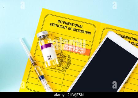 Passaporto di vaccinazione giallo, flacone di vaccino, siringa e smartphone con certificato di vaccinazione. Passaporto di vaccinazione per COVID-19 visualizzato su Smart Foto Stock