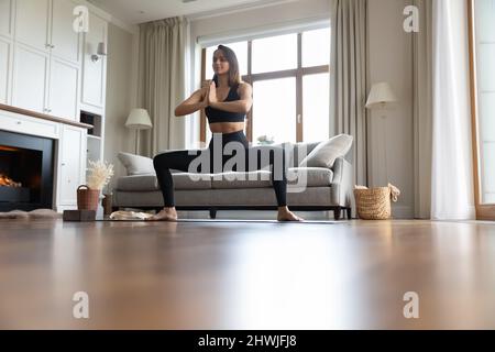 Donna in nero sportswear praticare yoga, fare Somo Squat posa Foto Stock