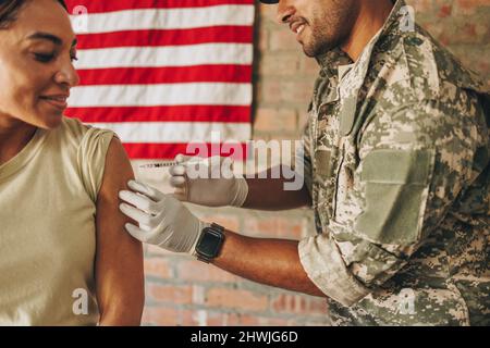 Esercito medic vaccinare una soldato femminile contro la malattia di coronavirus. Medico militare degli Stati Uniti che inietta una soldato femminile con il covid-19 vac Foto Stock