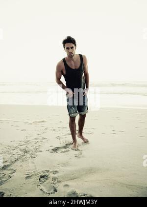 Non c'è posto migliore per rilassarsi. Scatto corto di un bel giovane uomo sulla spiaggia. Foto Stock