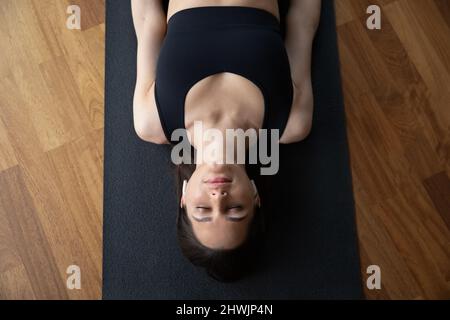 Sopra vista donna ascoltare musica meditativa giacente nel Corpse asana Foto Stock