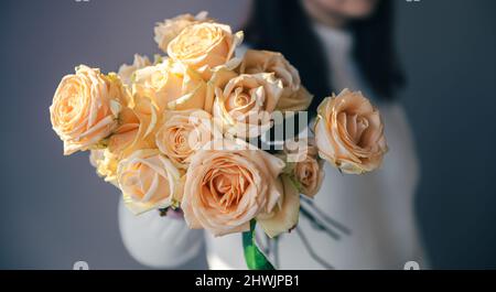 Primo piano delle rose arancioni nelle mani femminili. Foto Stock