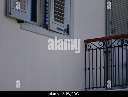 Antica facciata rurale con persiane in legno blu chiaro e un balcone ringhiera in ferro battuto su un muro imbiancato a Nafplio, Grecia. Foto Stock