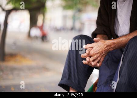 Anziani urbani. Scatto ritagliato di un vecchio uomo seduto fuori. Foto Stock