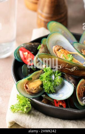 Deliziose cozze asiatiche al vapore con peperoncino rosso, cipolla verde, curcuma e aglio. Primo piano Foto Stock