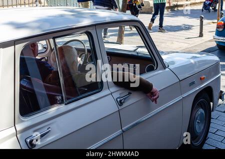 Vecchio uomo con il braccio di una macchina classica. Renault bianca 8. Foto Stock