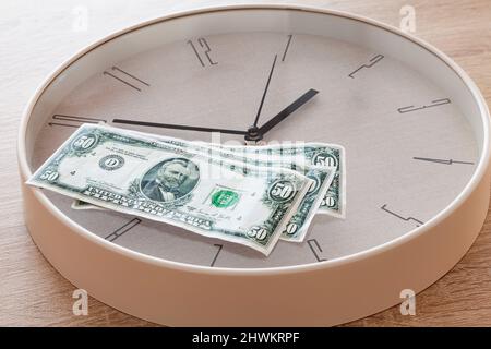 Ci sono tre bollette da 50 dollari USA su un grande orologio a tutto tondo. L'orologio colpisce da dieci a due. Foto Stock