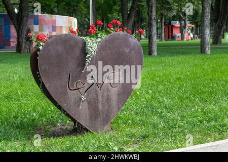 KHARKIV, UCRAINA - 3 AGOSTO 2021: Questo è un vaso di fiori a forma di cuore e l'iscrizione Amore nel Parco della Città. Foto Stock