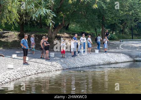 KHARKIV, UCRAINA - 3 AGOSTO 2021: Le persone non identificate partecipano ad un'attrazione per catturare i pesci in uno stagno artificiale nel parco di Sarzhin Yar. Foto Stock