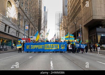 I sostenitori marciano lungo 4th Avenue durante un rally contro l'invasione russa dell'Ucraina a Seattle sabato 5 marzo 2022. Centinaia hanno partecipato al Foto Stock