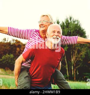 donna uomo outdoor coppia anziano felice lifestyle pensione insieme sorridente amore piggyback attivo maturo Foto Stock