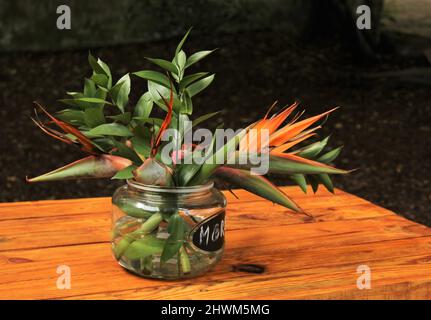 Vaso di vetro con fiori su un tavolo di legno Foto Stock