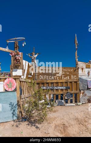 Protesta e ammonimenti sui cartelli sulla recinzione che corrono tra Slab City e East Jesus, due insediamenti off-the-grid sul lato est del sale Foto Stock