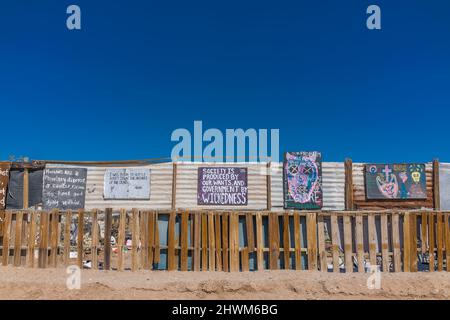 Protesta e ammonimenti sui cartelli sulla recinzione che corrono tra Slab City e East Jesus, due insediamenti off-the-grid sul lato est del sale Foto Stock