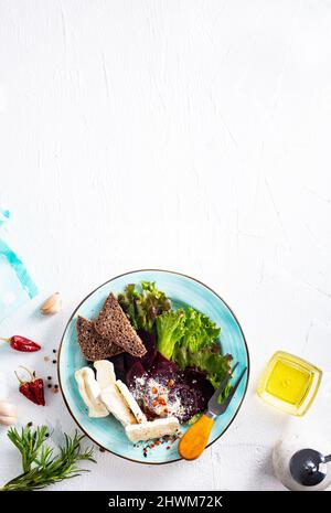 Camambrato, insalata di barbabietole e pane su piatto blu Foto Stock