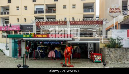 Un negozio di articoli sportivi e altri punti vendita al dettaglio tra cui un ristorante cinese lungo la banchina di Vilamoura, Portogallo. Foto Stock