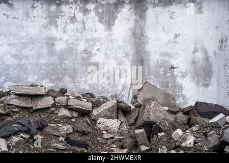 Rifiuti di costruzione sotto forma di un mucchio di detriti di calcestruzzo sullo sfondo di un muro di calcestruzzo. Sfondo. Foto Stock