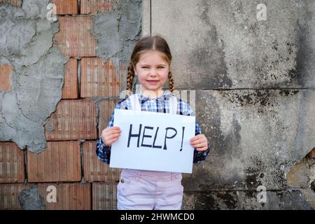 Bambina che tiene un poster con AIUTO scritto a sostegno della pace. Concetto di "nessuna guerra” in Ucraina e nel mondo. Conflitto russo a sostegno dei piselli Foto Stock