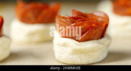 torta di peperoni a forma di rosa, pasta con salame, pasta sfoglia fatta in casa pronta per la cottura. Foto Stock