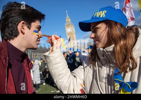 Londra, Regno Unito. 6th marzo 2022. Una donna dipinge una bandiera Ucraina sulla guancia di un collega protestante in Piazza del Parlamento, dove si sono riunite persone per protestare contro l'invasione russa dell'Ucraina e per chiedere la fine della guerra. Credit: Kiki Streitberger/Alamy Live News Foto Stock