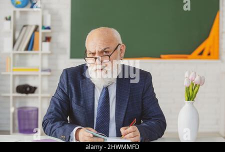 Professore tenendo un libro e indicando con un bastone di legno isolato su sfondo bianco. Conoscenza e concetto di istruzione tradizionale. Foto Stock