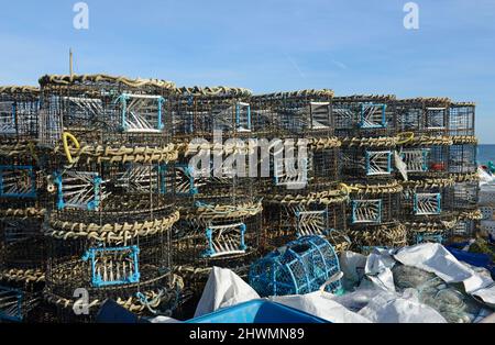 Molti aragoste e granchi creel o pentole accatastati sulla spiaggia a Hastings, East Sussex, Regno Unito, in attesa di dispiegamento sotto le onde. Foto Stock