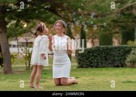 madre e figlia soffiano bolle di sapone all'aperto Foto Stock