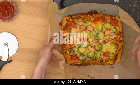 Focaccia italiana fatta in casa con pomodori ciliegini e peperoncino primo piano su rustico sfondo di legno. Foto Stock