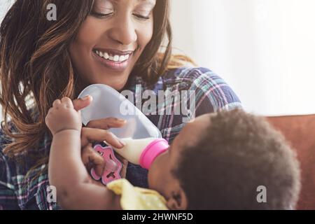 Somebodys affamato. Scatto corto di una madre giovane che alimenta la sua bambina a casa. Foto Stock