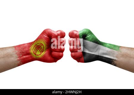 Due mani si pugno l'una all'altra su sfondo bianco. Bandiere di paese dipinse i pugni, concetto di crisi di conflitto tra kirghizistan ed emirati arabi uniti Foto Stock