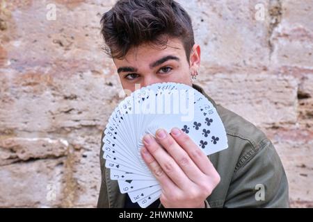Mago di strada nascosto dietro un pacco di carte in mano Foto Stock