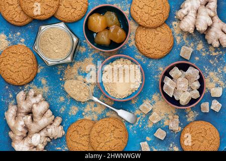 Zenzero in polvere, radice di zenzero, zenzero cristallino e zenzero a gambo con biscotti fatti in casa di zenzero su sfondo blu Foto Stock