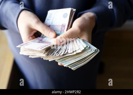 La Russia rubbe le banconote in mano durante la guerra in Ucraina. Inflazione, sanzioni e caduta del concetto di economia russa. Risparmio e budget in calo. Foto di alta qualità Foto Stock