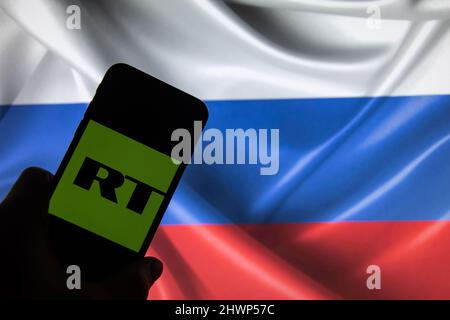 Rheinbach, Germania 4 marzo 2022, il logo del marchio "Russia Today" sul display di uno smartphone davanti a una bandiera russa (in primo piano sul logo del marchio) Foto Stock