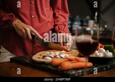 Donna caucasica tritare verdure in cucina Foto Stock